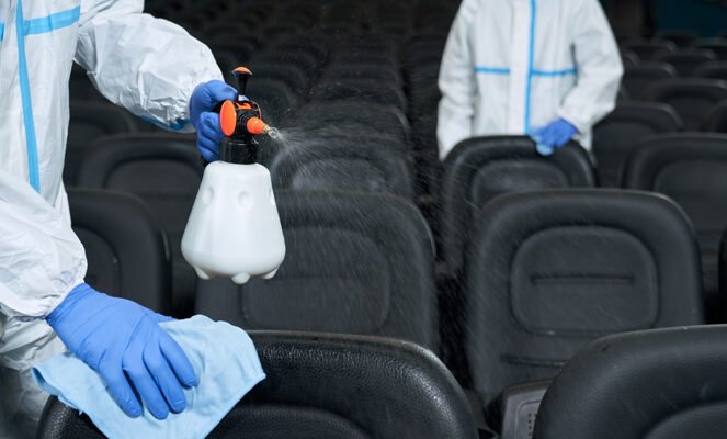 Workers cleaning chairs with disinfectants in cinema.